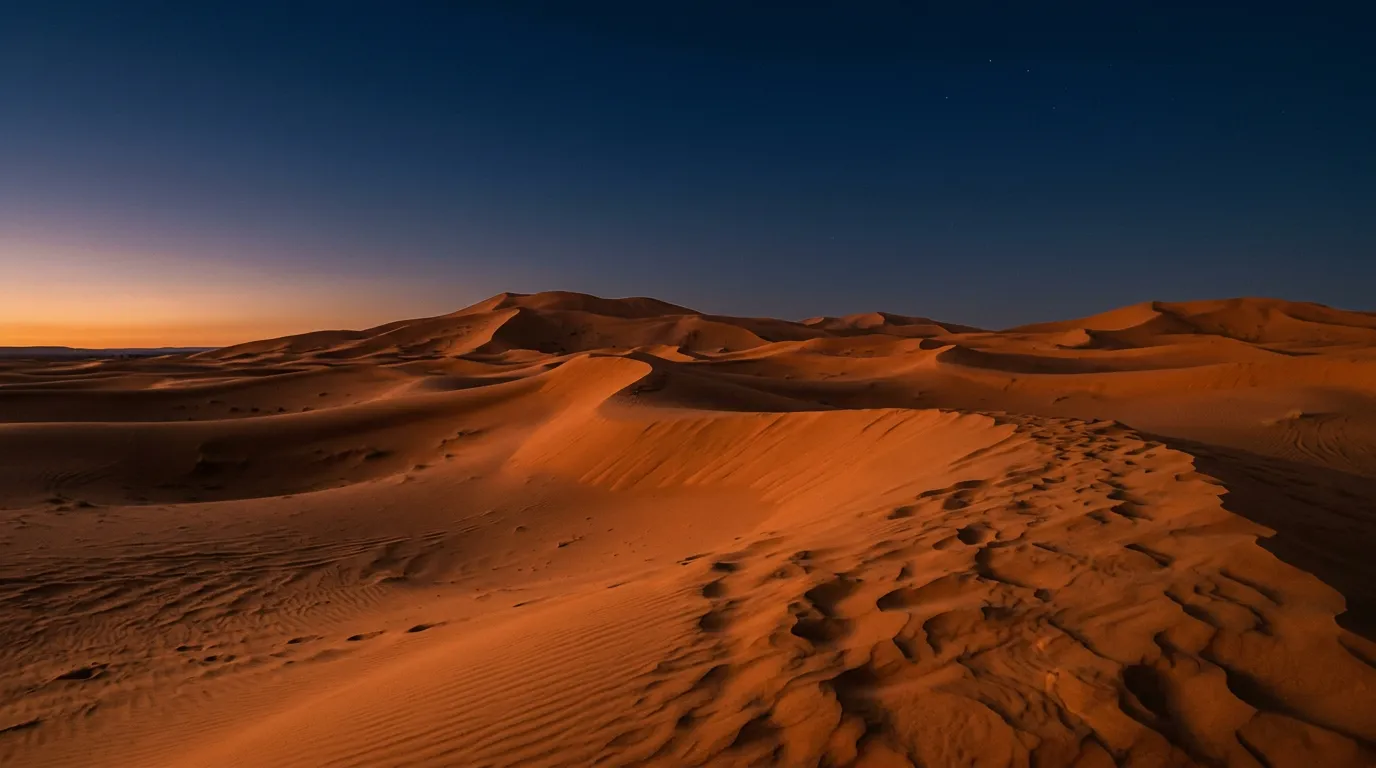 Wydmy Erg Chebbi o zachodzie słońca, pomarańczowy piasek na tle granatowego nieba